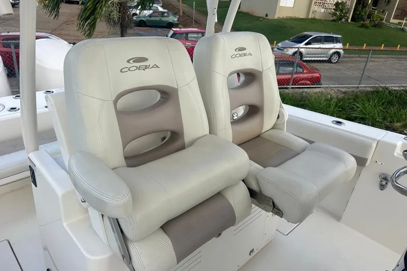 Slide: The Image of 2017 Cobia 296 Center Console boat seats, white and beige, outdoor setting. - 32