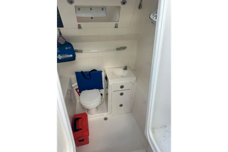 Slide: The Image of 2017 Cobia 296 Center Console boat interior with toilet, sink, and storage compartments. - 42
