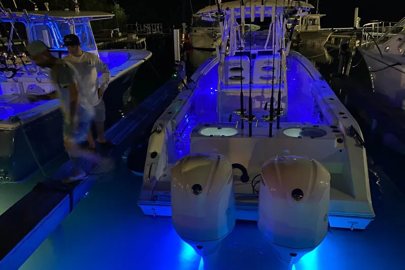 Slide: The Image of 2017 Cobia 296 Center Console boat illuminated with blue lights at night. - 5