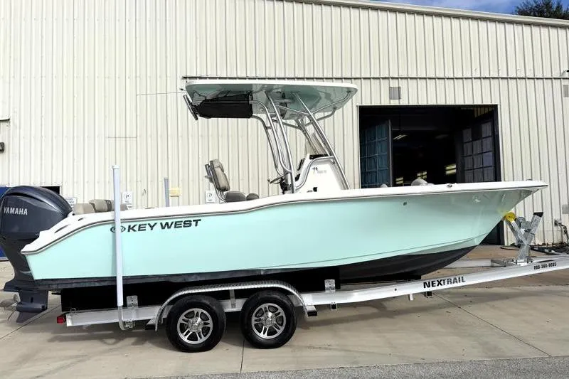 The Image of 2025 Key West 239 FS boat on trailer, parked outside a warehouse. - 0