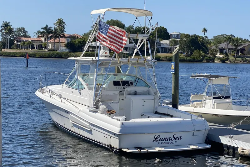 The Image of 2005 Stamas 370 Express boat docked, displaying an American flag, with waterfront homes in the background. - 0