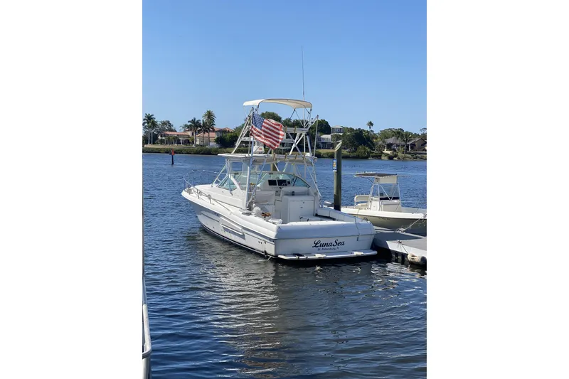 Slide: The Image of 2005 Stamas 370 Express boat docked, featuring an American flag and calm waters. - 125