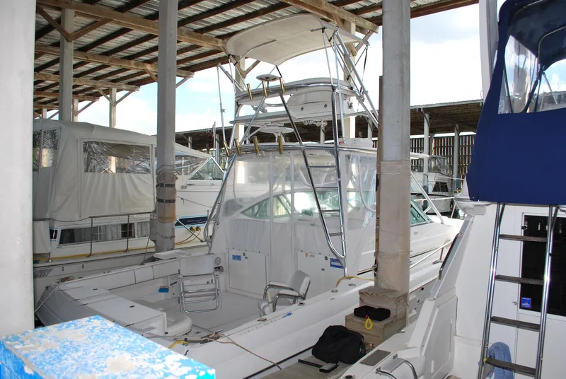 Slide: The Image of 2005 Stamas 370 Express boat docked in covered marina, surrounded by other vessels. - 2
