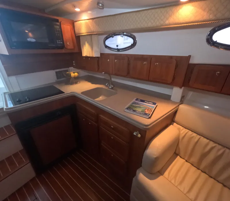 Slide: The Image of 2005 Stamas 370 Express yacht interior with kitchenette, wooden cabinets, and seating area. - 30