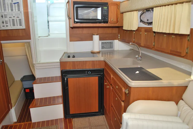 Slide: The Image of 2005 Stamas 370 Express yacht interior with kitchenette, microwave, and wooden cabinetry. - 37