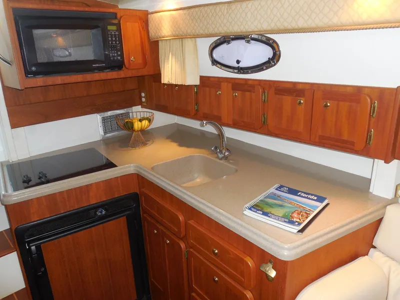 Slide: The Image of 2005 Stamas 370 Express yacht kitchen with wooden cabinets, microwave, and countertop sink. - 41