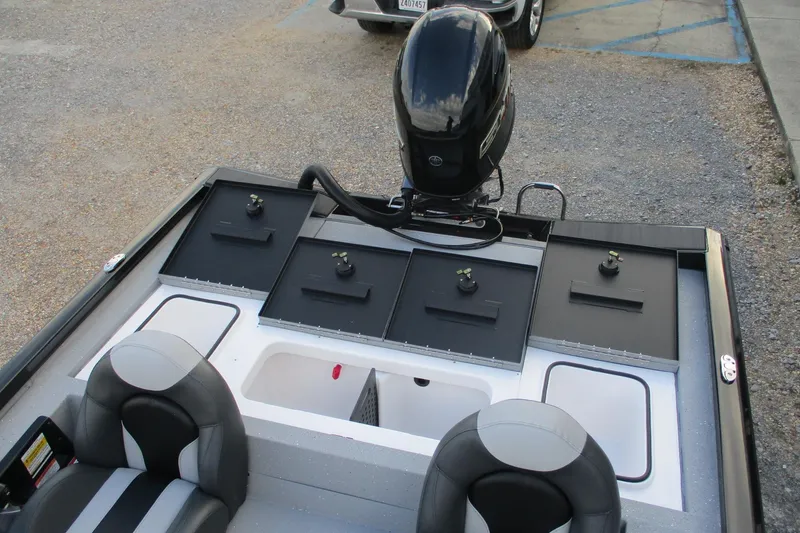 Slide: The Image of 2026 Vexus AVX189 boat interior with storage compartments and motor, parked on gravel. - 15