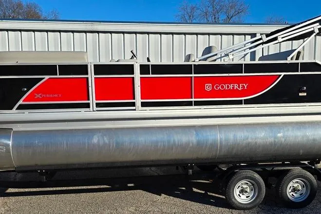Slide: The Image of 2026 Godfrey Experience 2286 SFL pontoon boat with red and black design on a trailer. - 9