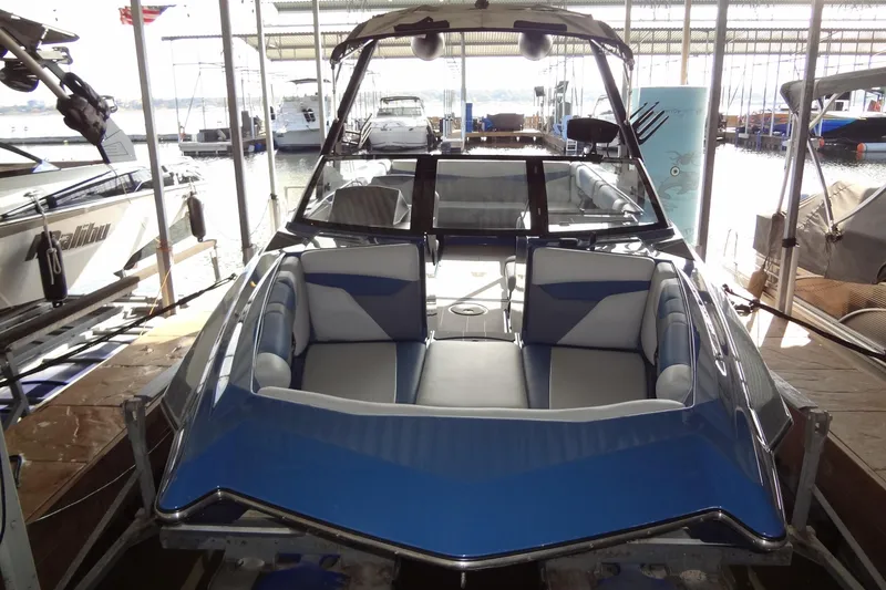 Slide: The Image of 2021 Axis A24 boat with blue and gray interior, docked in a marina. - 2