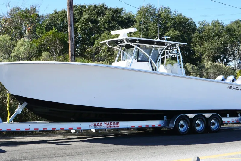 Slide: The Image of 2024 SeaHunter 39 Tournament boat on trailer, parked on roadside with trees in background. - 11
