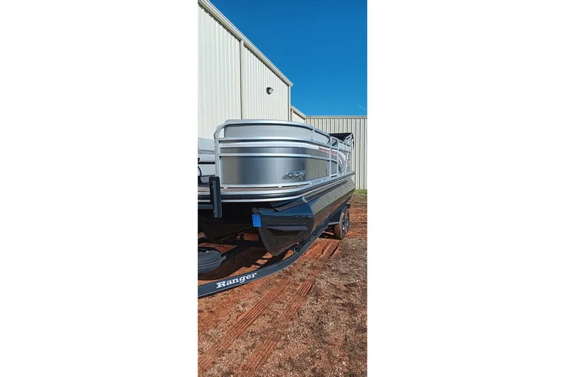 Slide: The Image of 2023 Ranger Reata 223C pontoon boat on trailer, parked outside a building. - 25