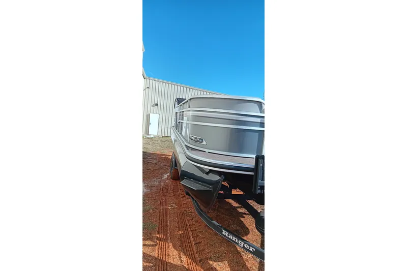 Slide: The Image of 2023 Ranger Reata 223C boat on trailer, parked outdoors under clear blue sky. - 26