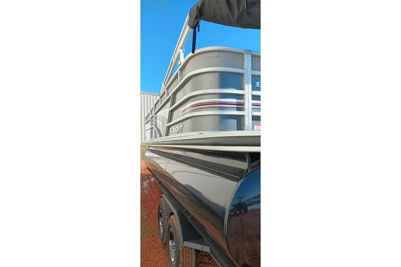 Slide: The Image of 2023 Ranger Reata 223C pontoon boat on trailer, side view under clear sky. - 9