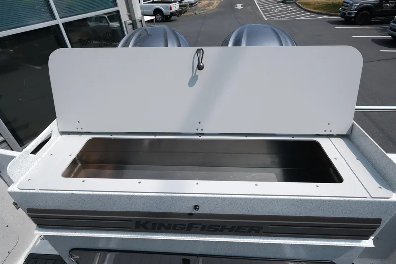 Slide: The Image of 2026 KingFisher 3025 XRS boat with open storage compartment, parked outdoors. - 25