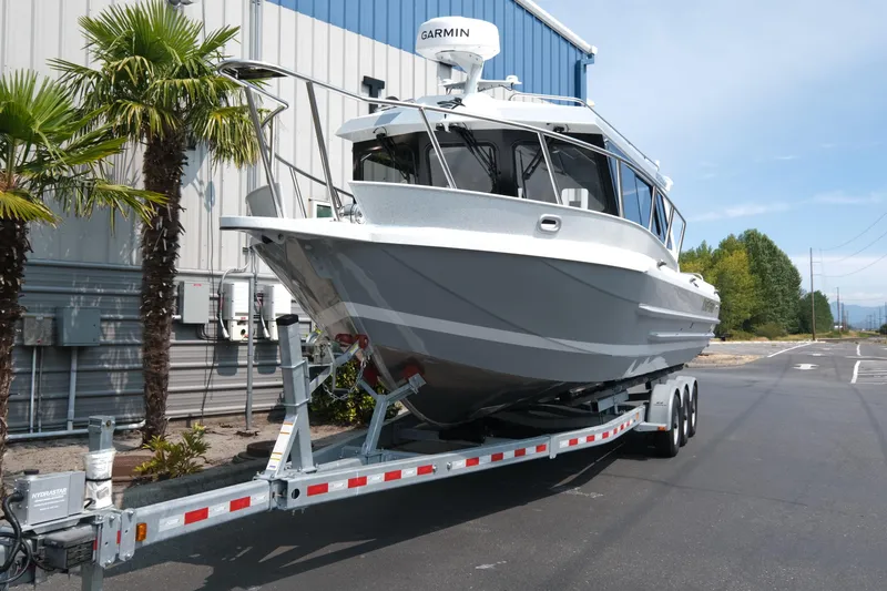 Slide: The Image of 2026 KingFisher 3025 XRS boat on trailer, parked near palm trees and industrial building. - 3