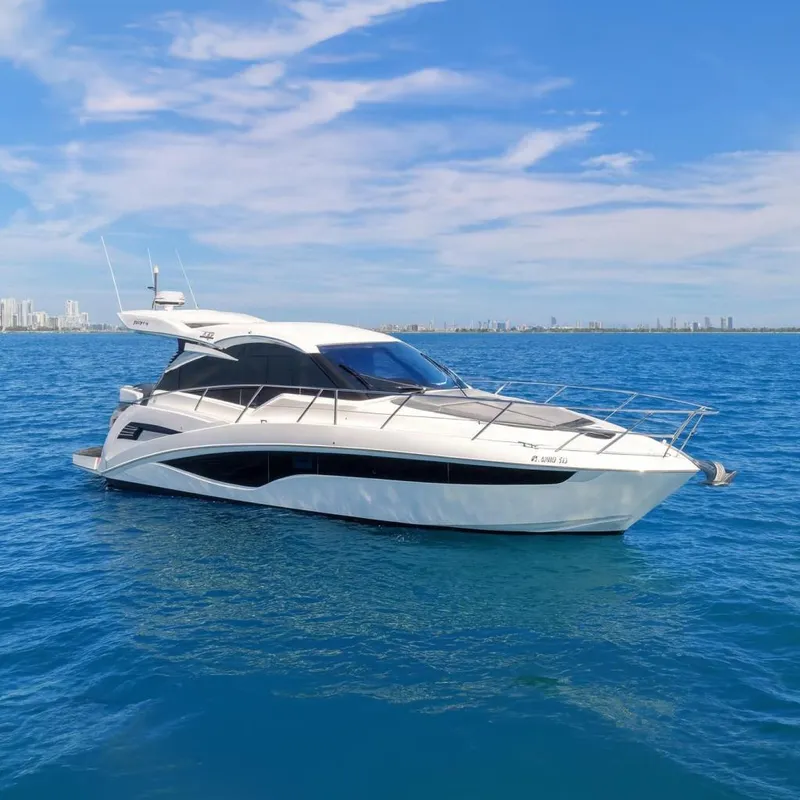 Slide: The Image of 2021 Galeon 425 HTS yacht cruising on blue ocean with city skyline in background. - 0