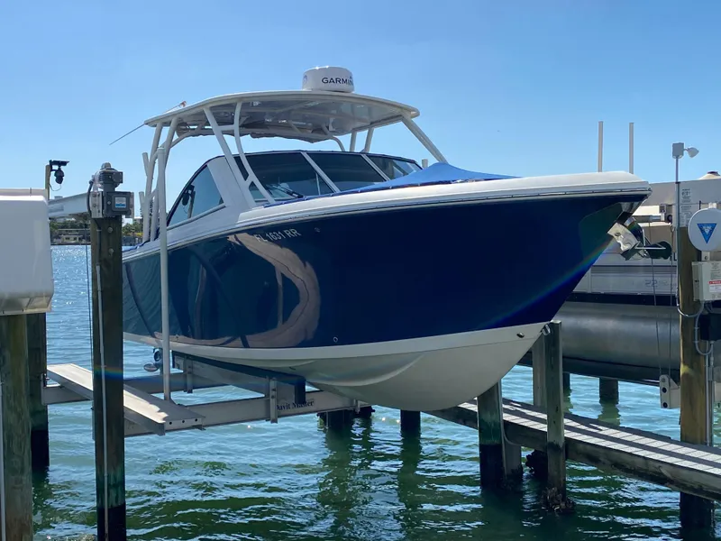 Slide: The Image of 2018 Sailfish 275 DC boat on a boat lift by the water. - 6