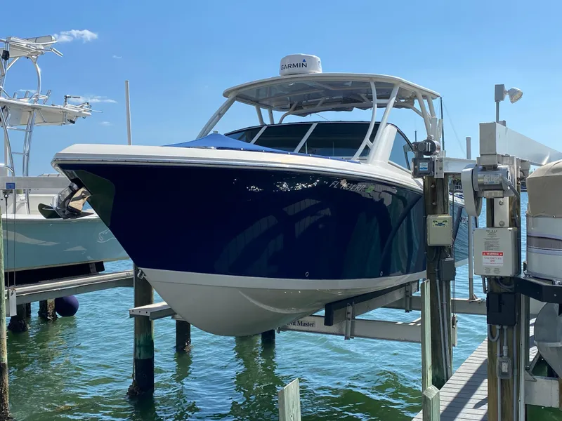 Slide: The Image of 2018 Sailfish 275 DC boat on a lift by the water. - 8