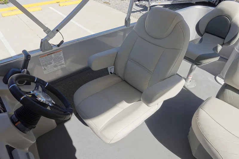 Slide: The Image of 2018 Sylvan Mirage 8522 boat interior with beige captain's chair and steering wheel. - 12