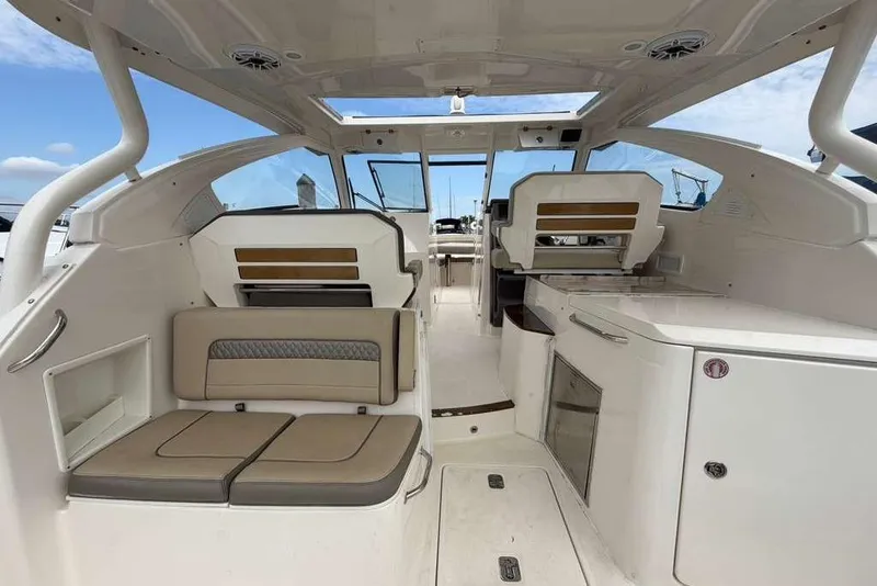 Slide: The Image of 2018 Pursuit DC 365 Dual Console interior with seating and storage, under a clear sky. - 14