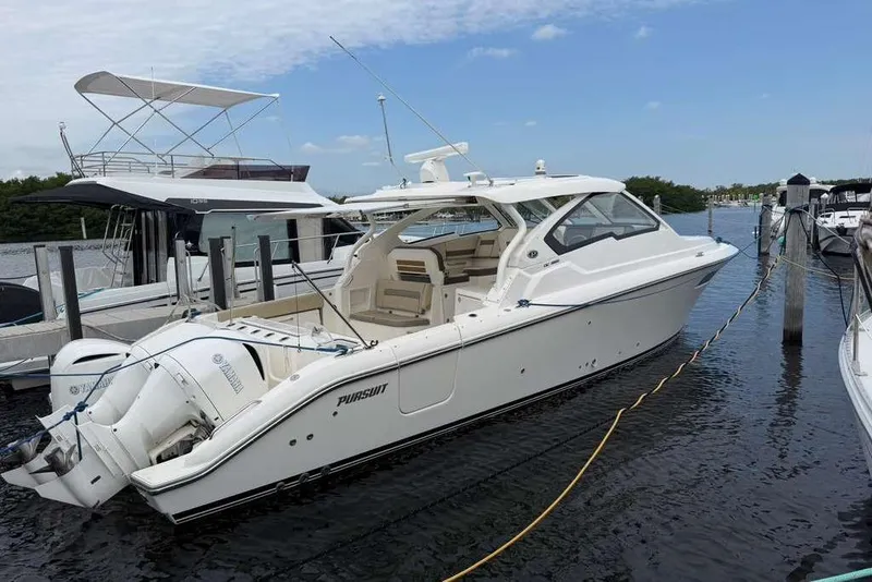 Slide: The Image of 2018 Pursuit DC 365 Dual Console boat docked at marina, featuring twin Yamaha engines. - 23