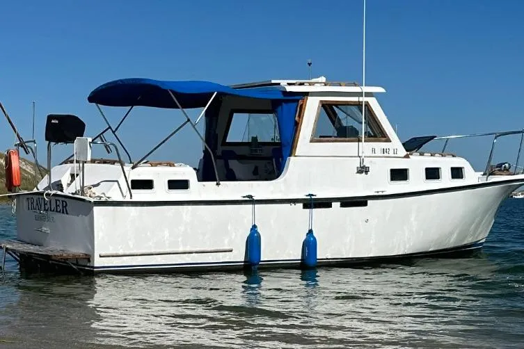 Slide: The Image of 1987 Albin Family Cruiser boat with blue canopy, docked in clear water. - 1