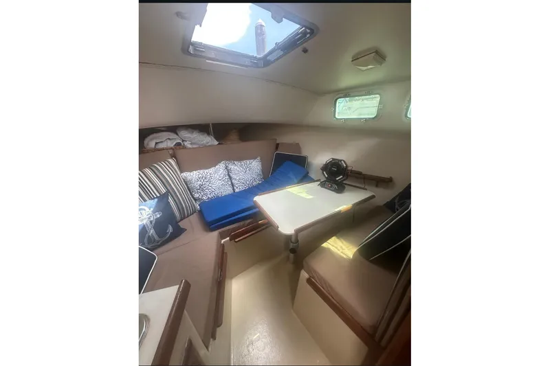 Slide: The Image of 1987 Albin Family Cruiser interior with cozy seating, cushions, and a small table. - 16