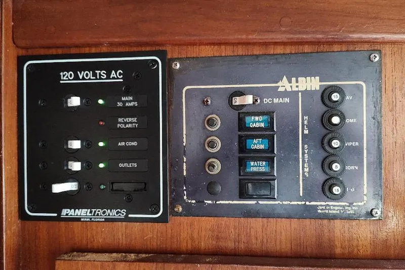 Slide: The Image of 1987 Albin Family Cruiser electrical panel with AC and DC controls, featuring switches and indicators. - 19