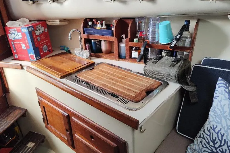 Slide: The Image of 1987 Albin Family Cruiser kitchen area with wooden cabinets and countertop accessories. - 21