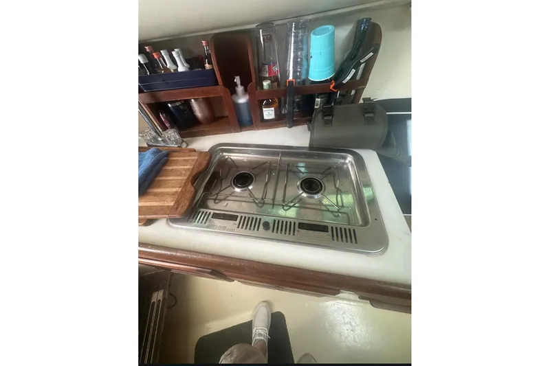 Slide: The Image of 1987 Albin Family Cruiser kitchen with stove, cutting board, and storage shelves. - 22