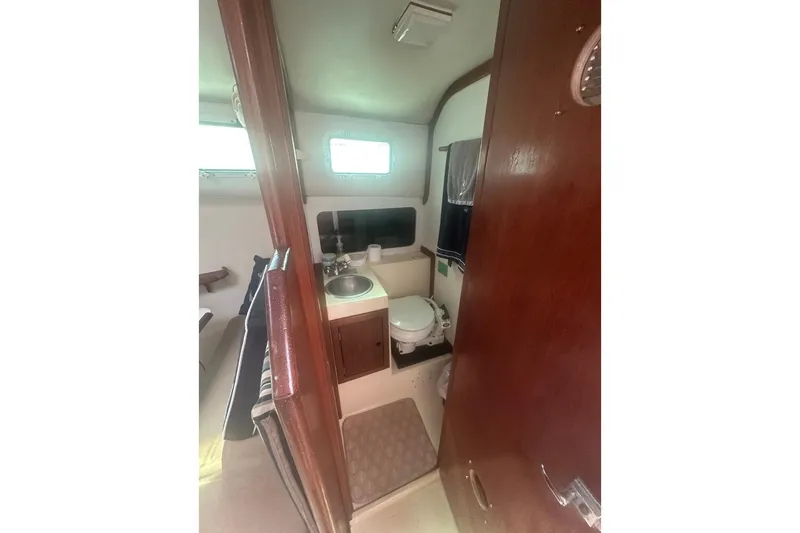 Slide: The Image of 1987 Albin Family Cruiser bathroom with sink, toilet, and wooden cabinetry. - 23