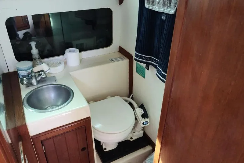Slide: The Image of Compact bathroom in a 1987 Albin Family Cruiser boat with sink and toilet. - 24