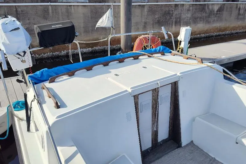 Slide: The Image of 1987 Albin Family Cruiser boat docked, featuring a covered outboard motor and deck seating. - 27