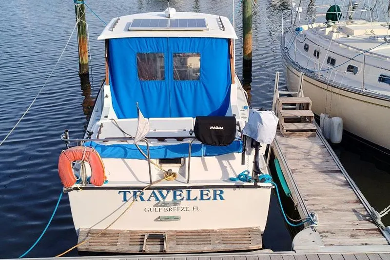 Slide: The Image of 1987 Albin Family Cruiser docked, featuring blue canopy and solar panel, named "Traveler." - 3