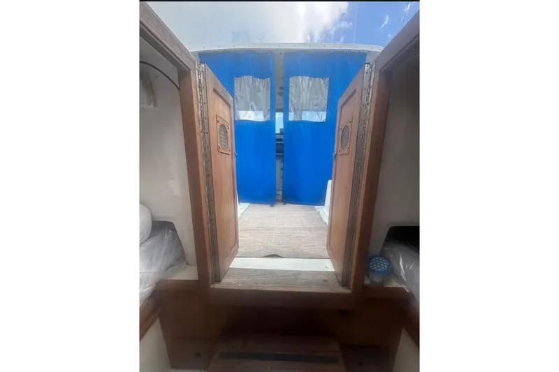 Slide: The Image of 1987 Albin Family Cruiser interior with wooden doors and blue curtains. - 30