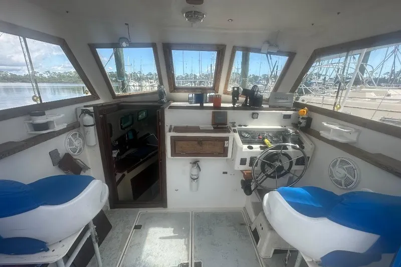 Slide: The Image of Interior of 1987 Albin Family Cruiser boat with helm, seating, and marina view. - 9