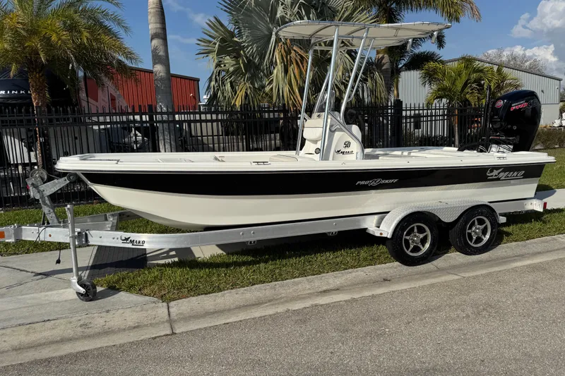 The Image of 2017 Mako Pro Skiff 19 CC boat on trailer, parked near palm trees. - 0