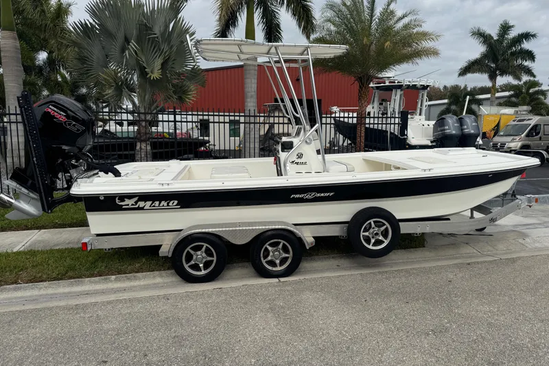 Slide: The Image of 2017 Mako Pro Skiff 19 CC boat on trailer, parked near palm trees. - 3