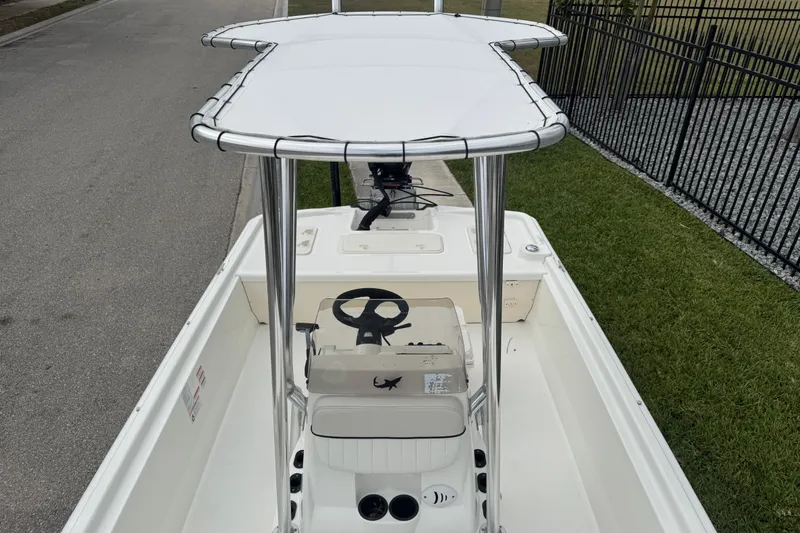 Slide: The Image of 2017 Mako Pro Skiff 19 CC boat with T-top, parked on a street. - 54