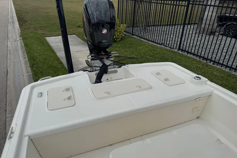 Slide: The Image of 2017 Mako Pro Skiff 19 CC boat with outboard motor, parked near a fence. - 57