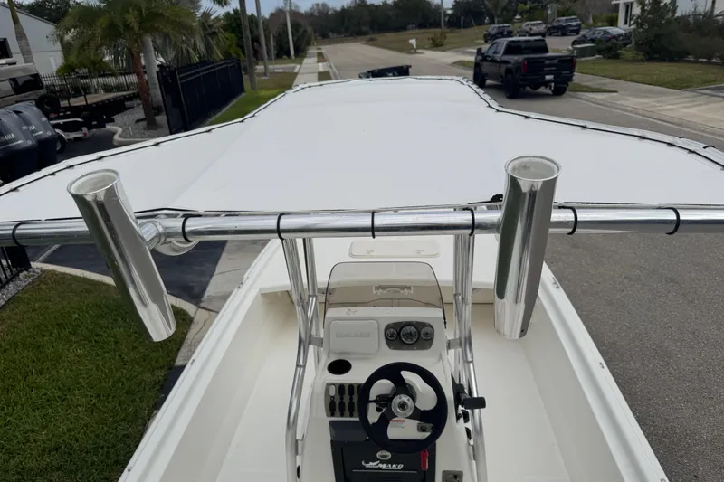 Slide: The Image of 2017 Mako Pro Skiff 19 CC boat with T-top and rod holders, parked on a street. - 65