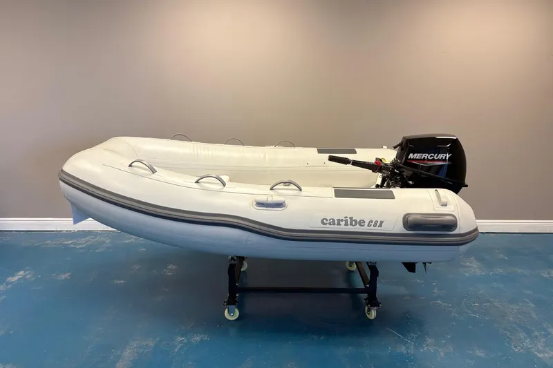 Slide: The Image of Inflatable Caribe 8X boat with Mercury motor, 2025 model, on display indoors. - 1