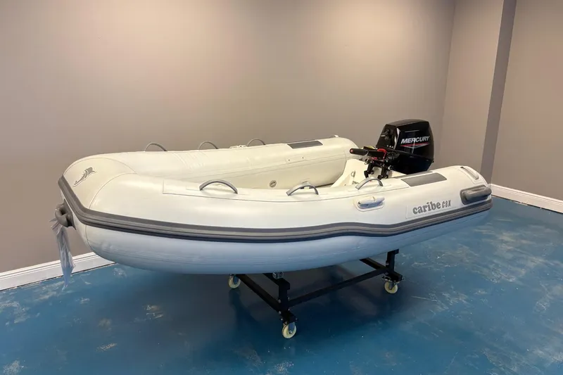 Slide: The Image of Inflatable Caribe 8X boat, 2025 model, with Mercury outboard motor on display indoors. - 2