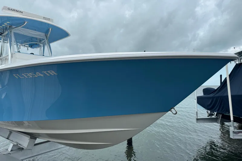 Slide: The Image of 2024 Contender 30 Tournament boat in blue, docked by the water under cloudy skies. - 7
