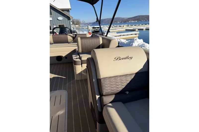 Slide: The Image of 2026 Bentley Pontoons Elite 223 Swingback Bench interior with luxurious seating by a snowy lakeside. - 10