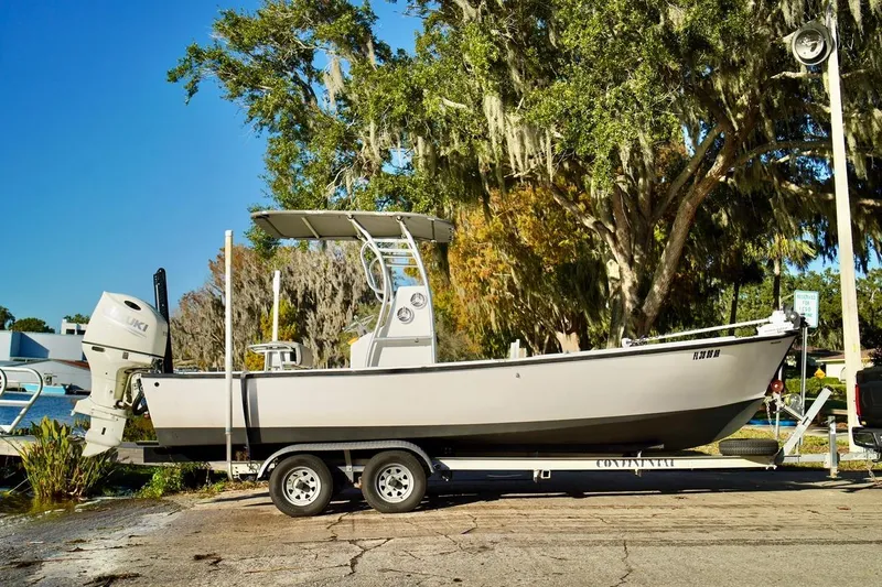 Slide: The Image of 1970 Aquasport 222 Flatback boat on trailer, parked near water, surrounded by trees. - 2