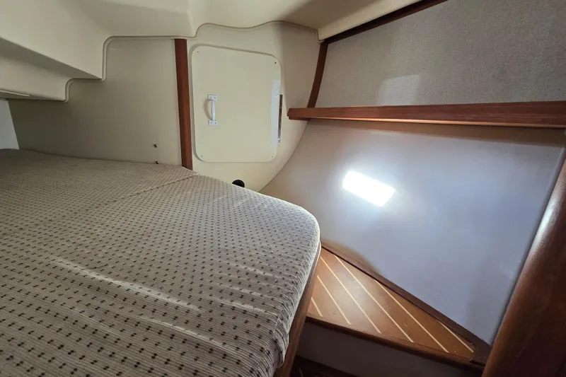 Slide: The Image of 2006 Island Packet 370 interior cabin with bed, wooden accents, and natural light. - 32