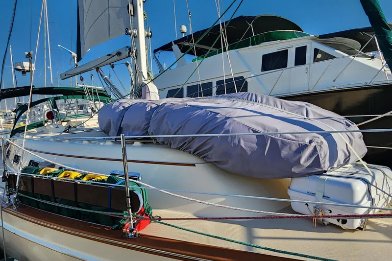 Slide: The Image of 2006 Island Packet 370 sailboat docked, featuring covered equipment and vibrant blue sky. - 6