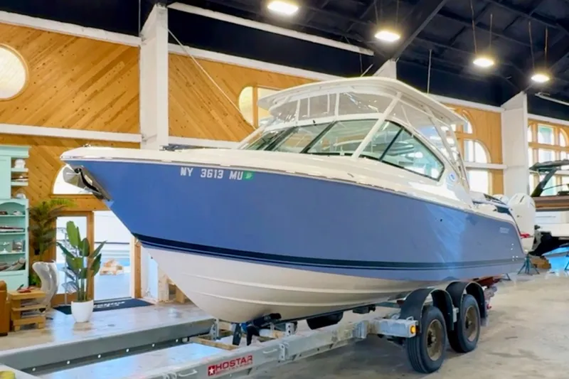 Slide: The Image of 2024 Pursuit DC 266 Dual Console boat displayed indoors on a trailer. - 0