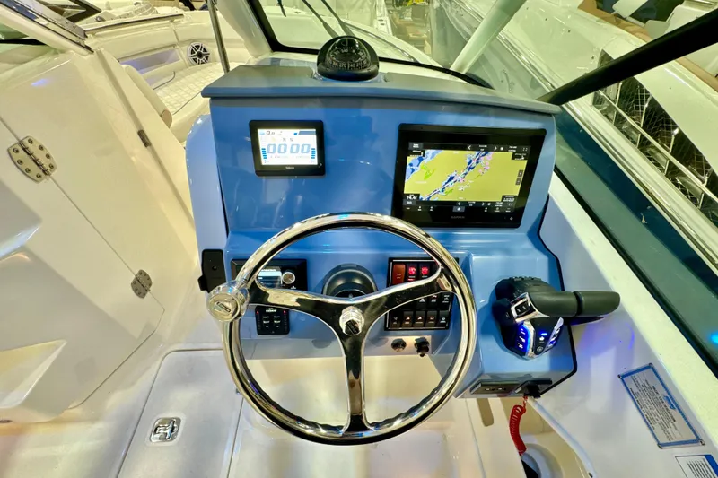 Slide: The Image of 2024 Pursuit DC 266 Dual Console boat dashboard with steering wheel and navigation screens. - 17
